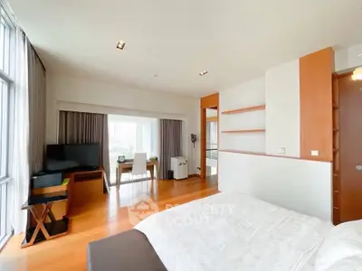 Spacious modern bedroom with hardwood floors and large windows offering natural light.