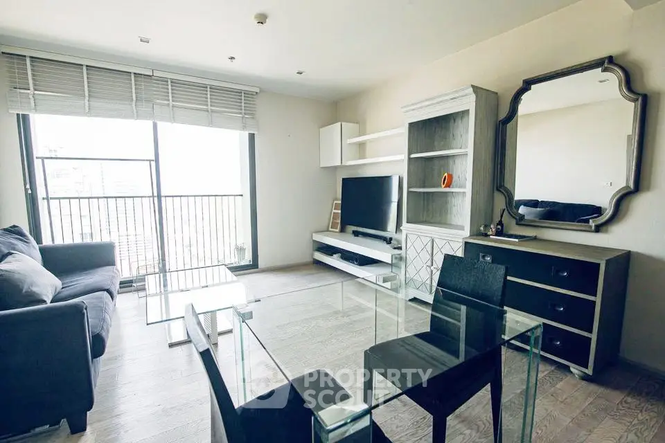 Modern living room with glass table, large TV, and stylish decor in a bright apartment.