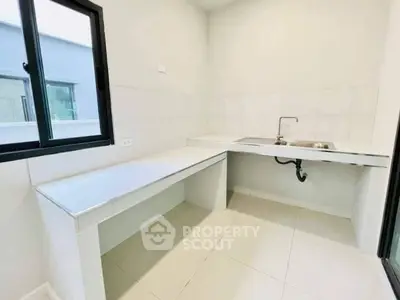 Modern minimalist kitchen with sleek countertops and ample natural light.