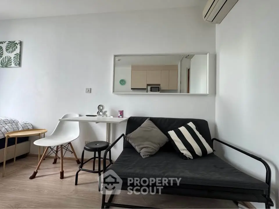 Modern studio apartment with cozy seating and dining area, featuring minimalist decor and air conditioning.