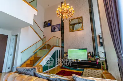 Luxurious living room with high ceiling, elegant chandelier, and modern staircase