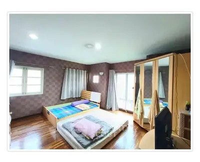 Spacious bedroom with wooden flooring and ample natural light