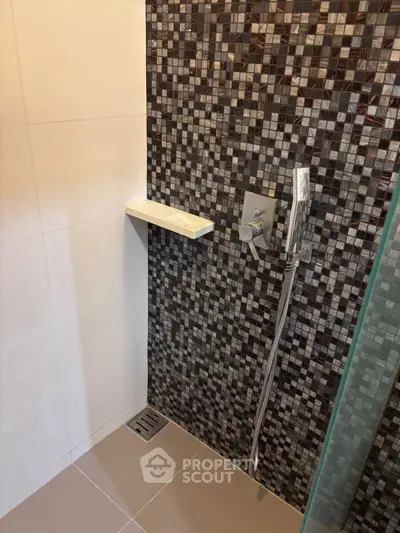 Modern bathroom shower area with stylish mosaic tiles and sleek fixtures