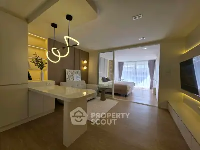 Modern open-plan living room with stylish lighting and cozy bedroom view