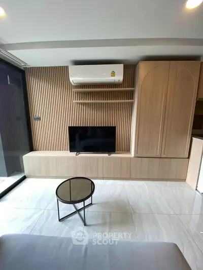 Modern living room with sleek wooden paneling and mounted TV, featuring a minimalist design.