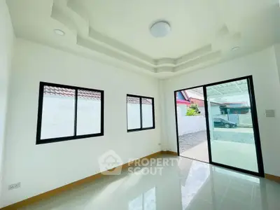 Bright and spacious room with large windows and sliding glass door leading to outdoor area.