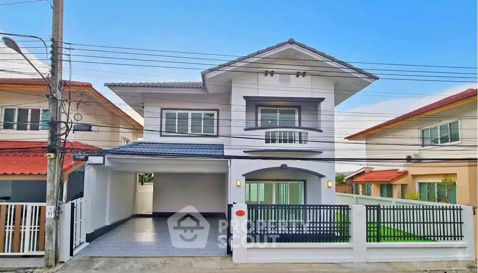 Modern two-story house with gated driveway and manicured lawn in suburban neighborhood.