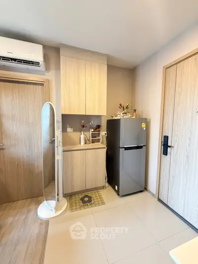 Modern kitchen with sleek fridge and stylish cabinetry in compact apartment