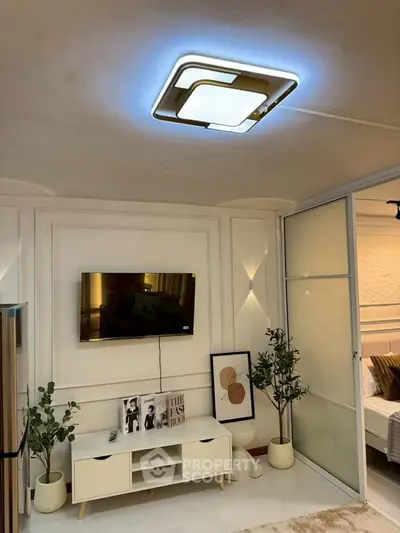 Modern living room with stylish ceiling light, TV, and elegant decor