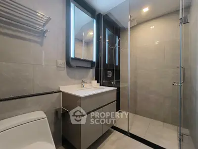 Modern bathroom with sleek design, glass shower, and illuminated mirror.