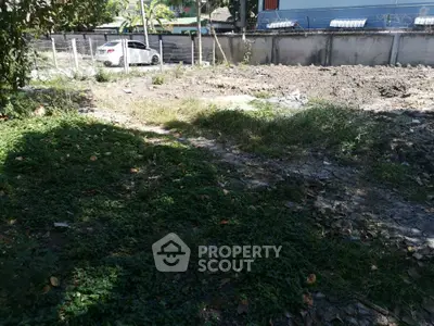 Vacant land plot with greenery and partial fencing, ideal for development opportunities.