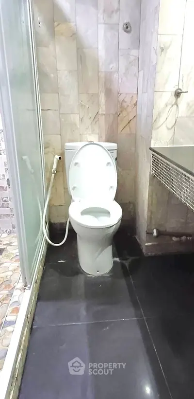 Modern bathroom with sleek black flooring and stylish tiled walls.