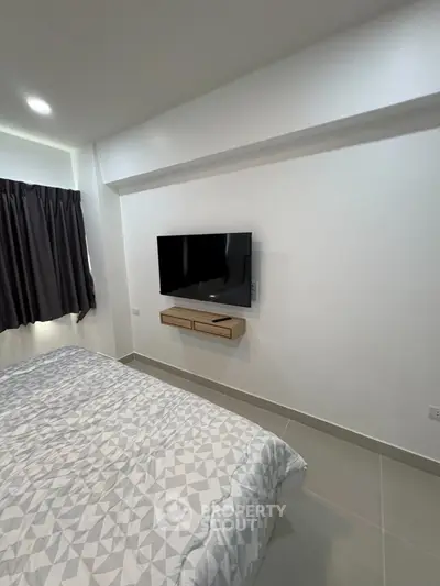 Modern bedroom with wall-mounted TV and stylish bedding