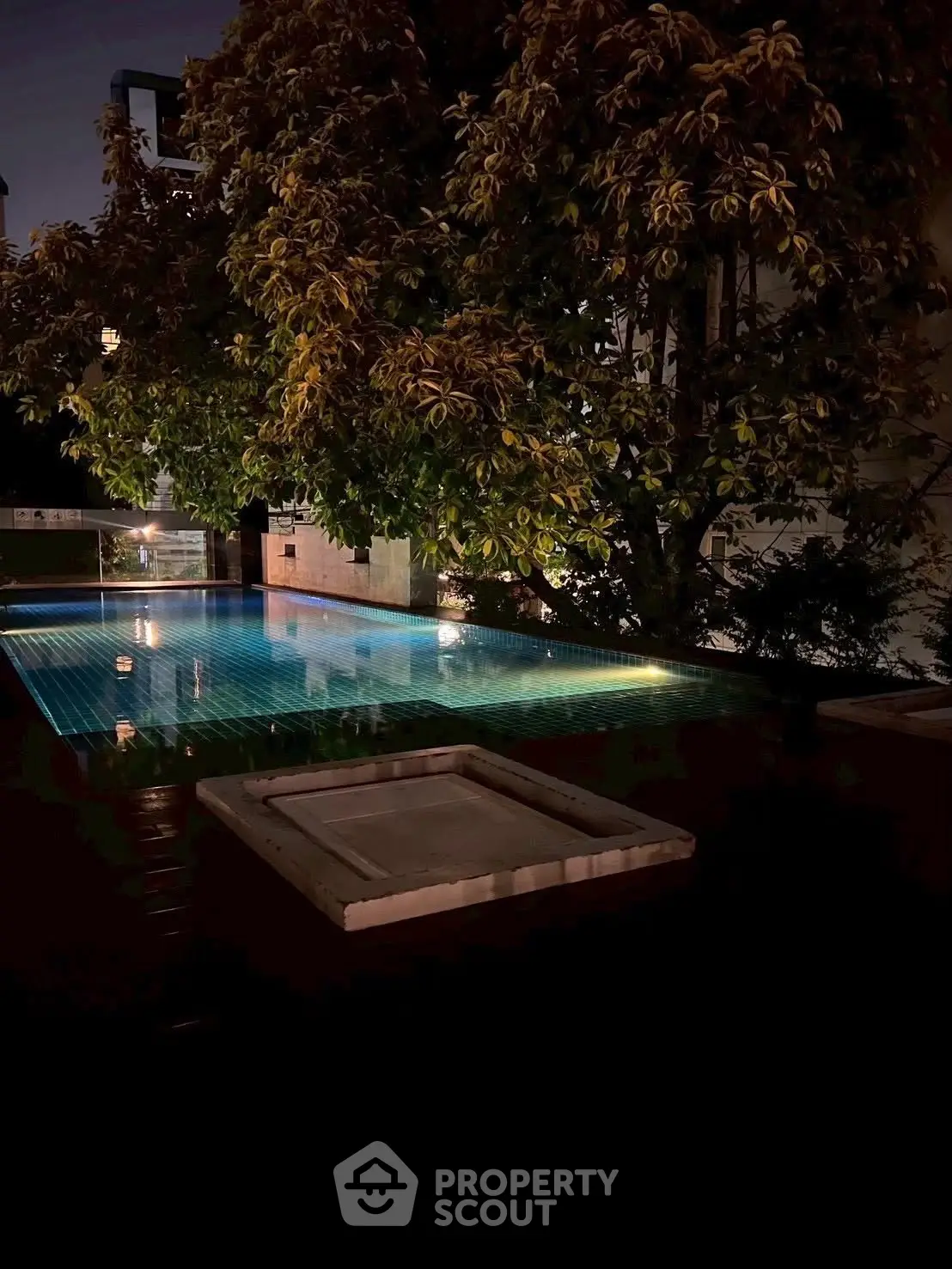Luxurious night view of a serene pool surrounded by lush greenery, perfect for relaxation.