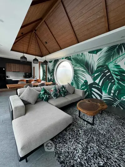 Luxurious living room with tropical-themed decor, featuring a spacious sectional sofa and unique wooden ceiling.