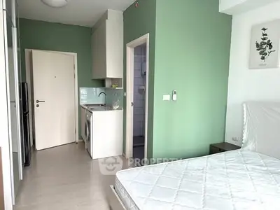 Modern studio apartment with green accent wall and compact kitchen area