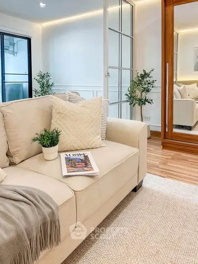 Stylish living room with cozy beige sofa, elegant decor, and mirrored wardrobe reflecting modern design.