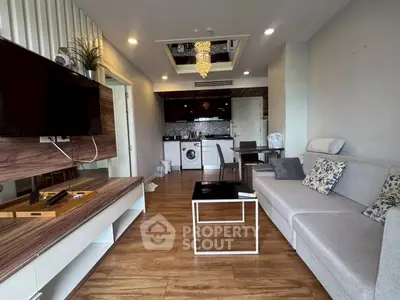 Modern living room with open kitchen, featuring stylish decor and wooden flooring.