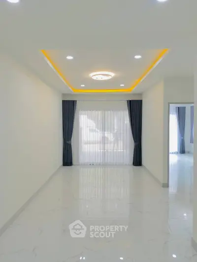 Spacious modern living room with elegant ceiling lights and large windows.