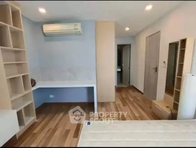Modern bedroom with wooden flooring, built-in shelves, and air conditioning unit.