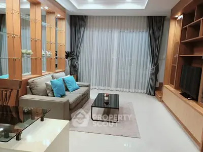 Modern living room with elegant decor, featuring a cozy sofa, stylish shelving, and large windows with curtains.