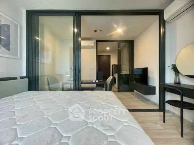 Modern studio apartment with glass partition, stylish furniture, and natural light.