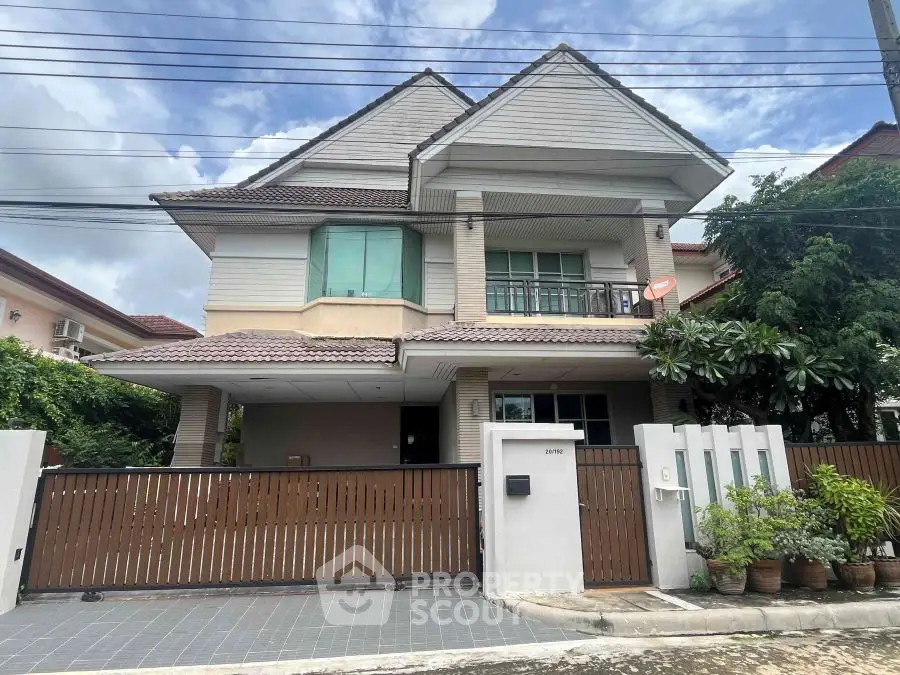 Charming two-story house with gated entrance and lush greenery, perfect for family living.