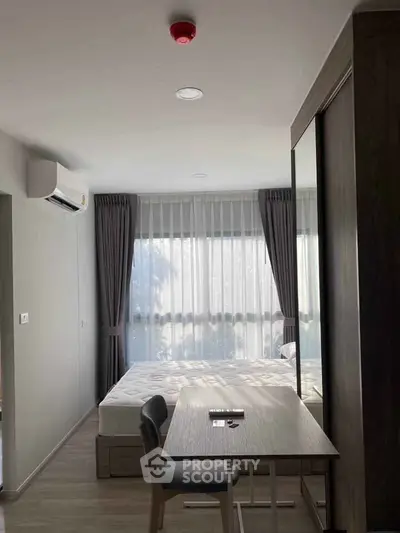 Modern bedroom with large window, desk, and air conditioning in a stylish apartment.