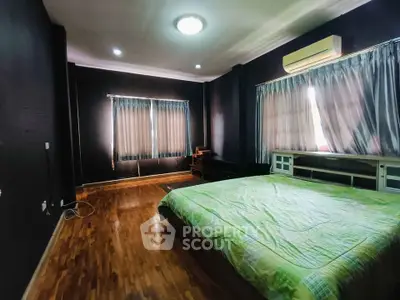 Spacious bedroom with wooden flooring and large windows for natural light