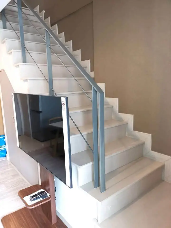 Modern interior staircase with sleek metal railing and wall-mounted TV in stylish home