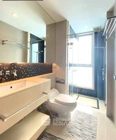 Modern bathroom with sleek fixtures and large mirror in a bright setting.