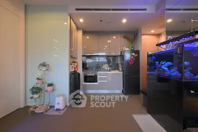 Modern kitchen with sleek cabinetry, built-in oven, and vibrant aquarium in stylish apartment.