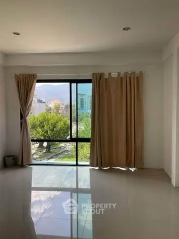 Spacious living room with large window offering scenic garden view, perfect for natural light lovers.