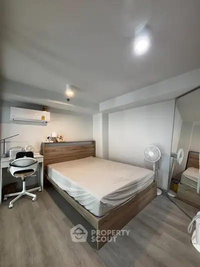 Modern bedroom with wooden bed, mirrored closet, and cozy workspace