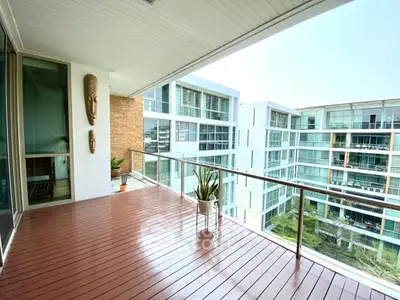 Spacious balcony with modern glass railing and city view in luxury apartment building.