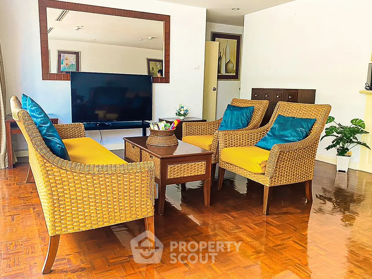 Charming living room with stylish wicker furniture and large TV, perfect for relaxation and entertainment.