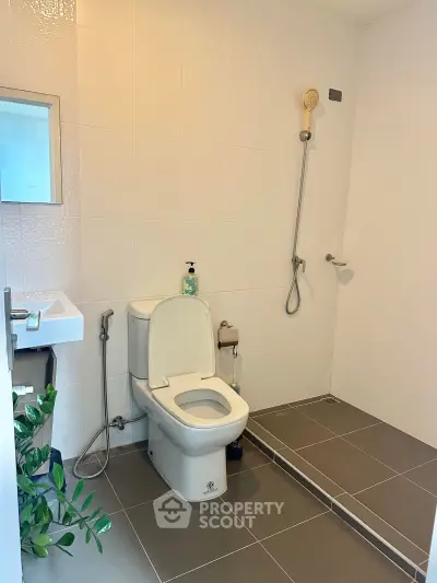 Modern bathroom with sleek design, featuring a toilet, shower, and stylish tiles.