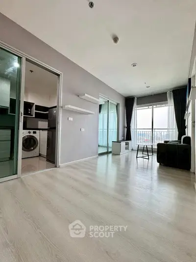 Spacious modern living room with balcony and laundry area in a stylish apartment.
