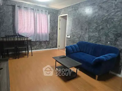 Modern living room with blue sofa and stylish gray walls, featuring a cozy dining area and wooden flooring.