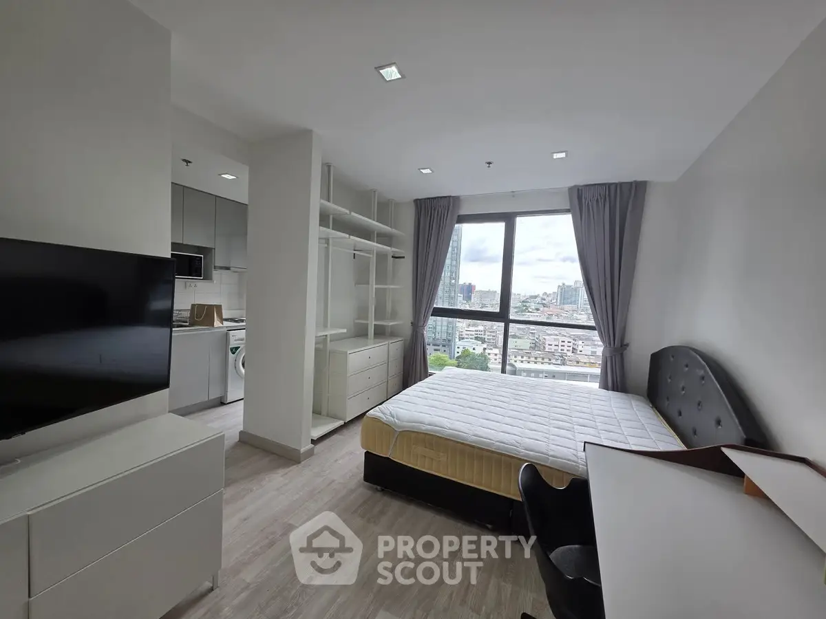 Modern bedroom with city view, featuring sleek furniture and large windows for natural light.