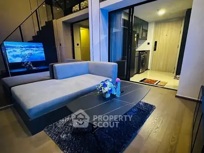 Modern living room with sleek furniture and open layout, featuring a stylish staircase and cozy ambiance.