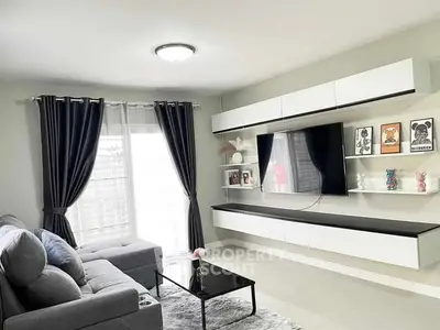 Modern living room with sleek furniture and large TV, featuring elegant curtains and stylish decor.