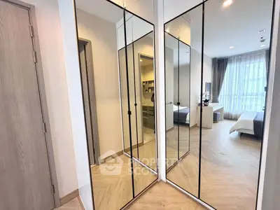 Spacious bedroom with mirrored closet doors and large window for natural light.