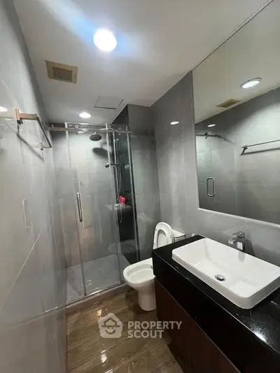 Modern bathroom with sleek glass shower and stylish vanity in contemporary apartment.