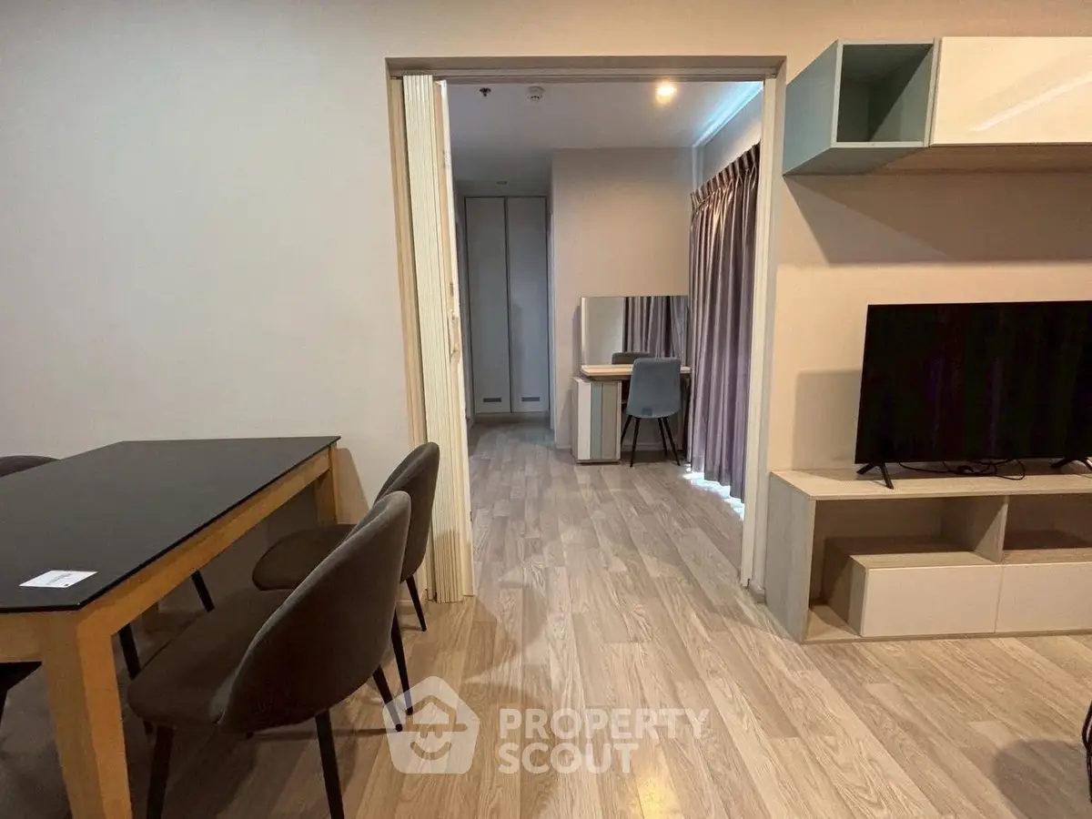 Modern living room with dining area and study nook, featuring sleek furniture and wood flooring.