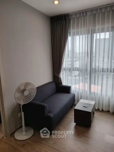 Modern living room with cozy sofa and city view through large window.