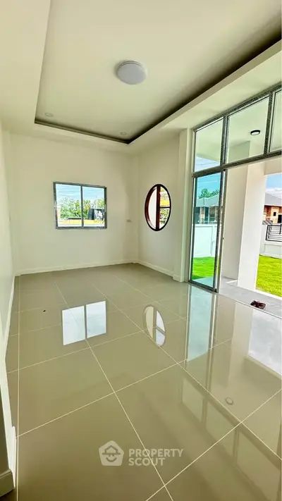 Spacious modern living room with large windows and glossy tiled floor