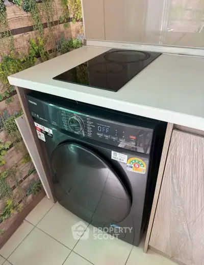 Modern kitchen with sleek appliances including a washing machine and electric stove.