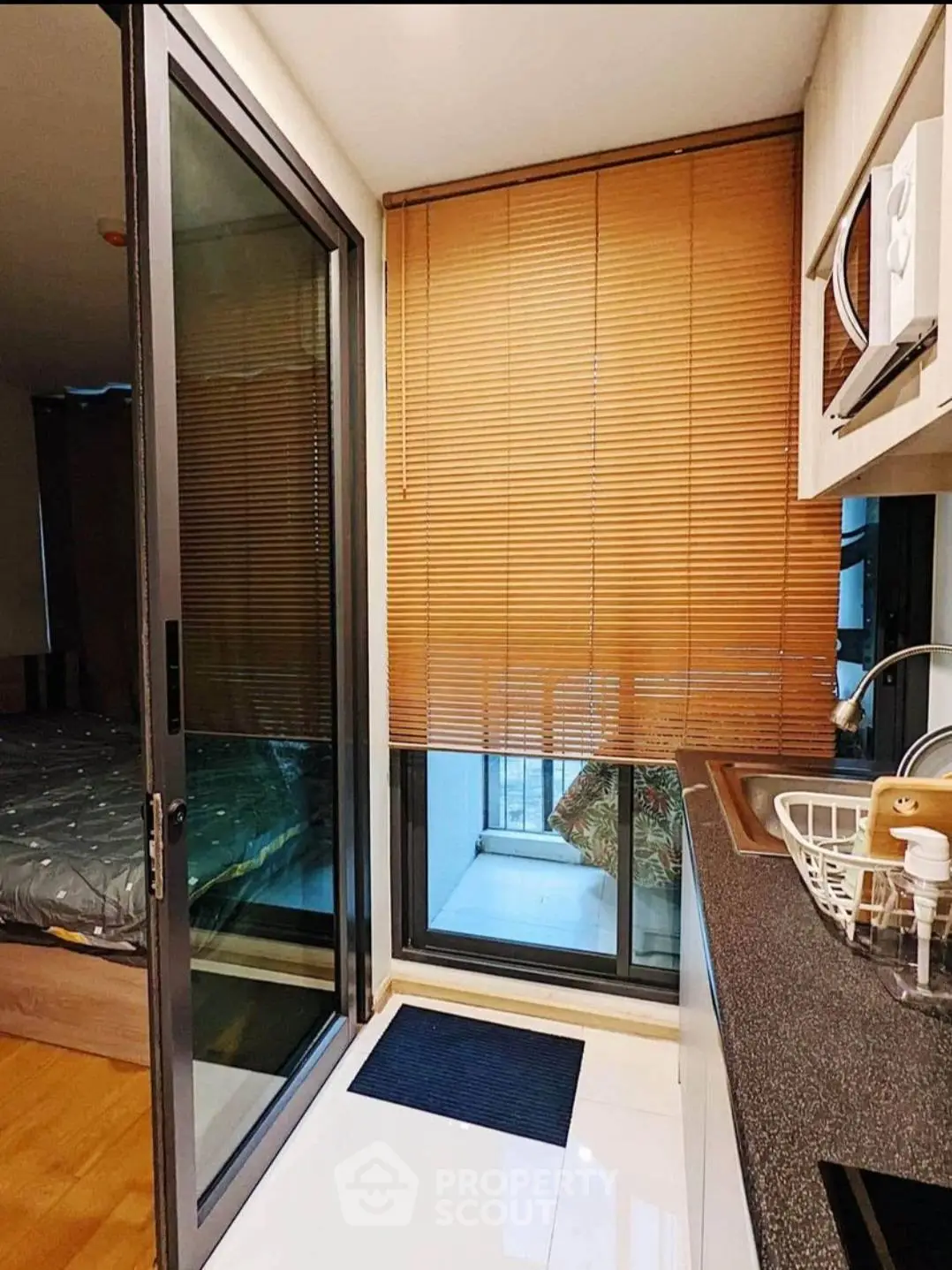 Cozy kitchen with sliding glass door and wooden blinds, adjacent to a bedroom.