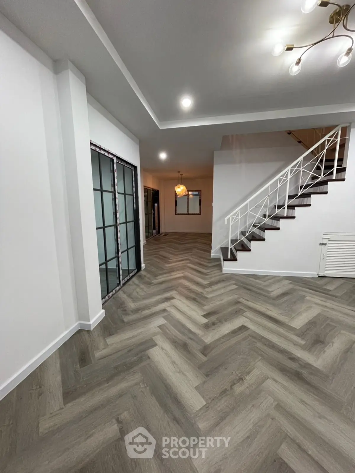 Spacious modern living room with stylish herringbone flooring and elegant staircase